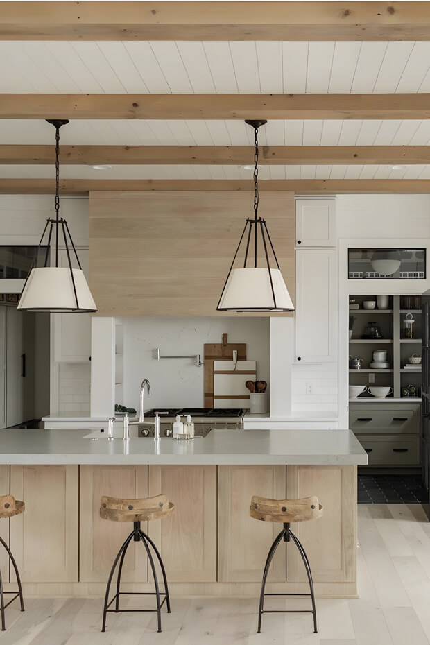 Cozy ambiance provided by three pendant lights hanging from wooden beams above kitchen island