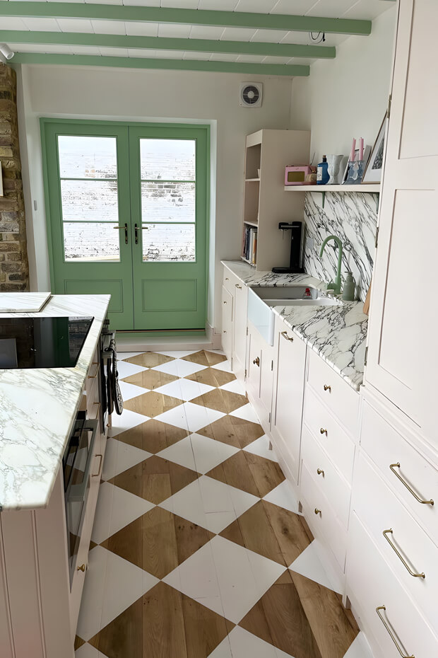 Kitchen with white cabinets, marble countertops, green door, and checkered floor